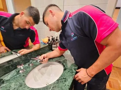 Two Pink Plumbing plumbers working on a marble vanity basin