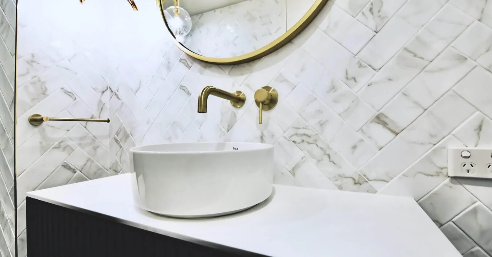 Marble herringbone bathroom vanity with brass tapware and round basin