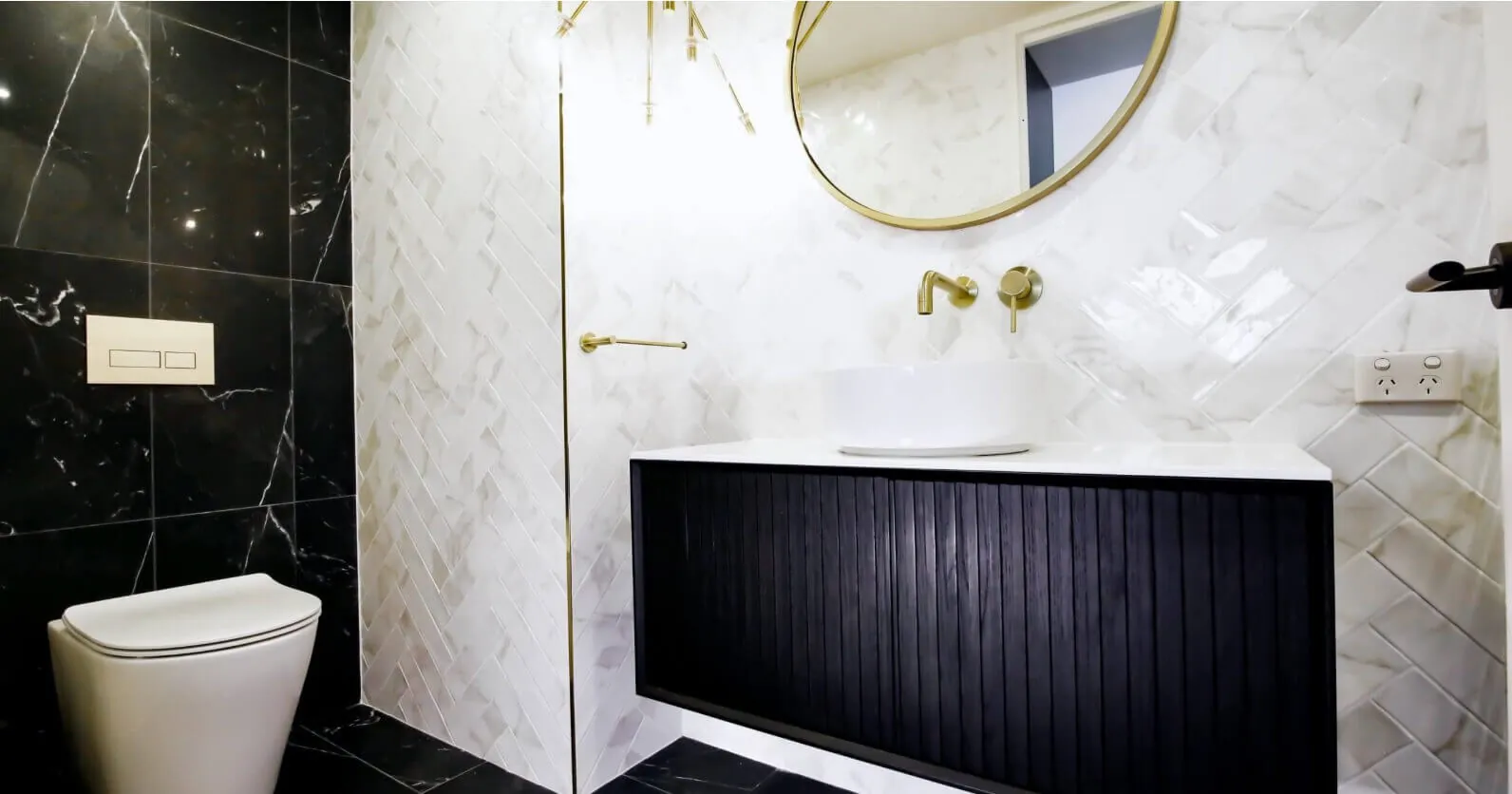 Marble bathroom renovation with black vanity and brass towel rail