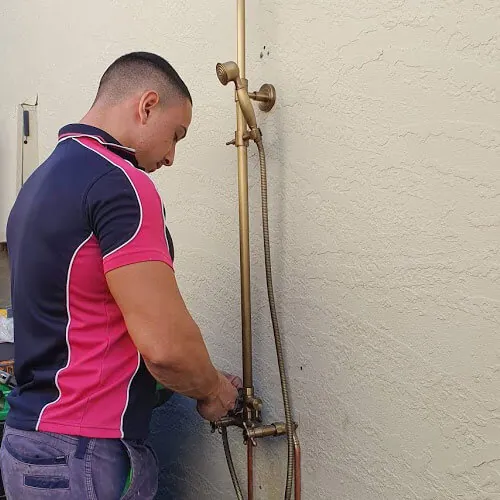 Pink Plumbing plumber servicing an outdoor brass shower